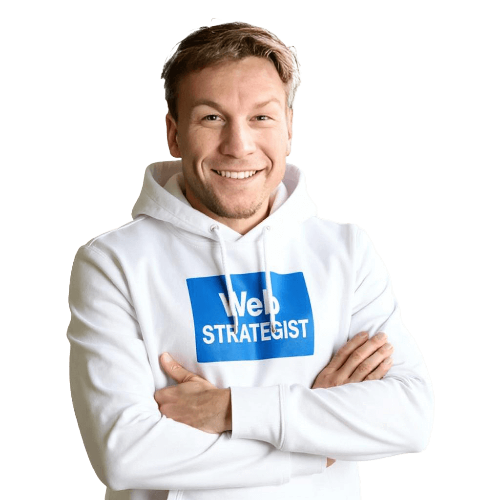 A man smiling at his desk with a laptop and notebook.